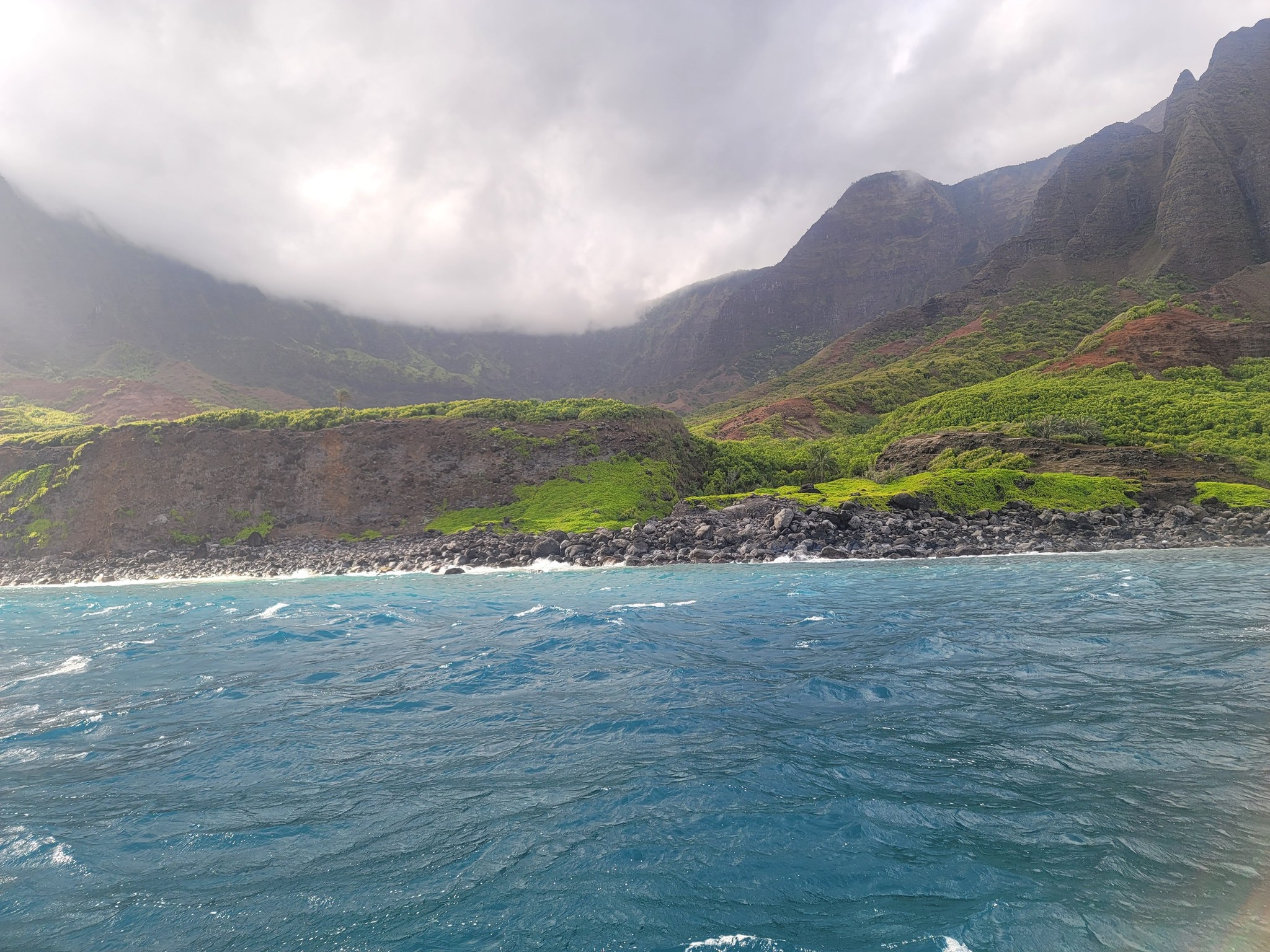 The Napali coast seen from a boat, green ridges falling straight into the sea